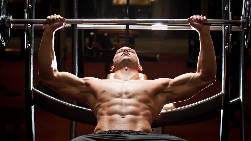 Shirtless man lifting barbell on bench.