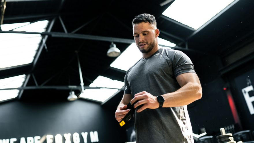 Man in sportschool met lifting belt om zijn middel.