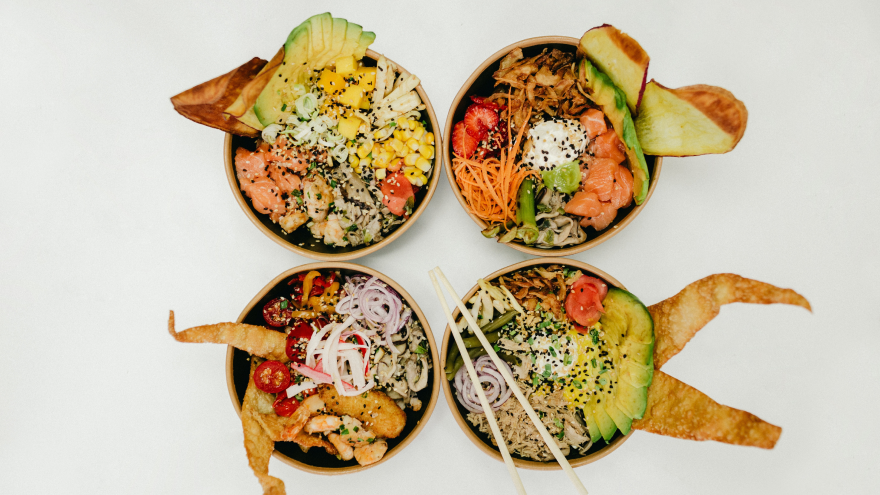 Vier bunte Poke Bowls mit frischem Gemüse, Reis und Toppings auf hellem Hintergrund.