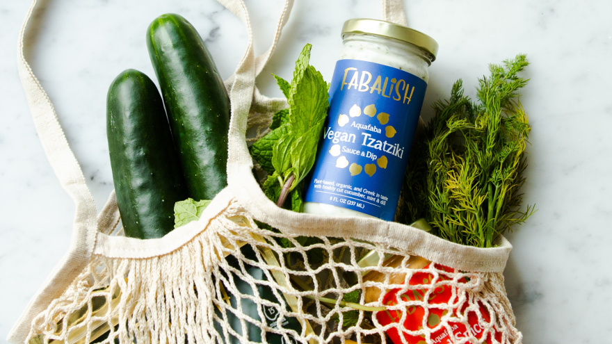 Vegan tzatziki and fresh vegetables in reusable grocery bag.