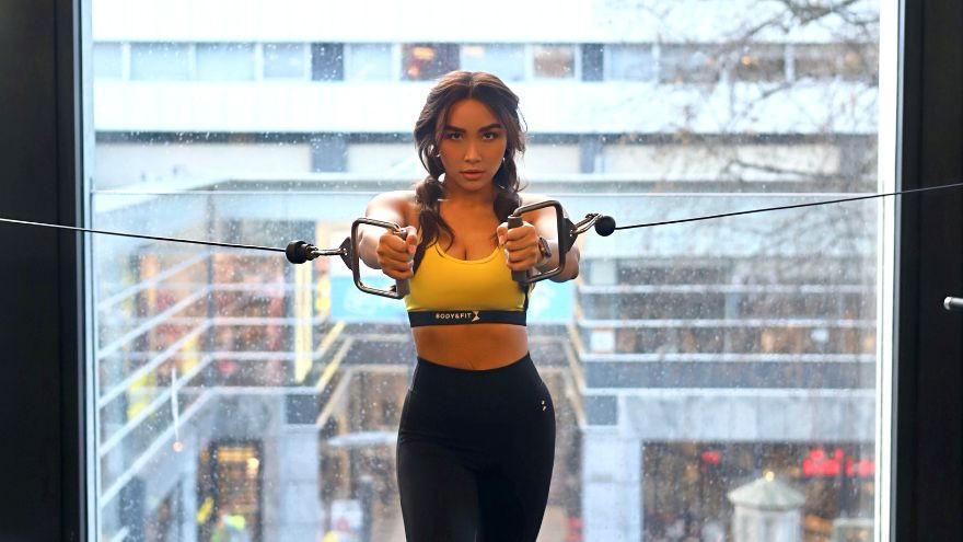 Vrouw traint borstspieren met kabelmachine in sportschool.