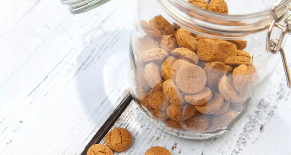 Vorratsglas mit knusprigen runden Keksen auf weißem Tisch.