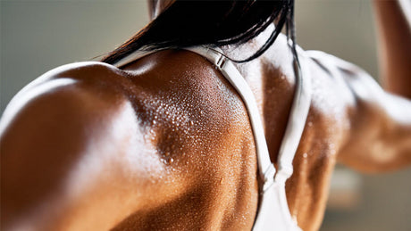 Close-up of woman’s sweaty back in white sports bra.