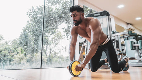 Man met ab roller traint buikspieren in sportschool.