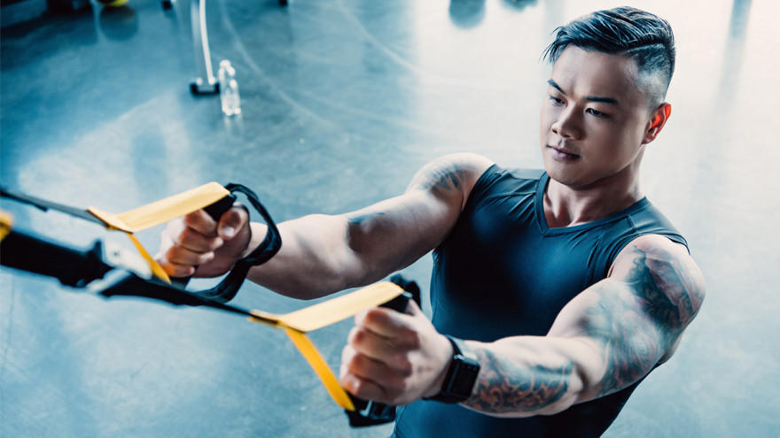 Man traint met TRX suspension banden in fitnessruimte.