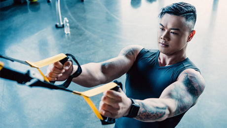 Man traint met TRX suspension banden in fitnessruimte.