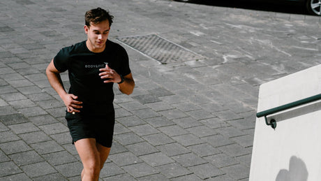Man rent trappen op in sportoutfit van Body&Fit.