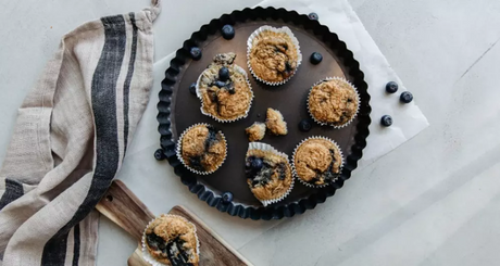Blauwebessenmuffins in bakvorm op betonnen ondergrond.