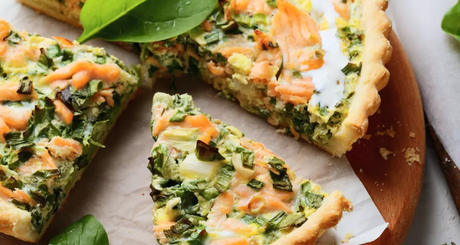 Quiche mit Lachs, Spinat und Lauch in Stücken serviert.