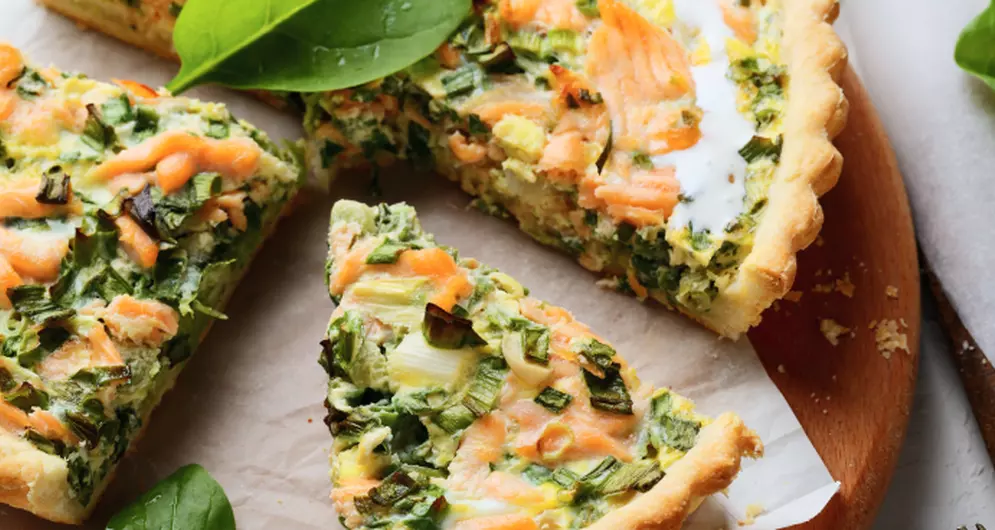 Quiche mit Lachs, Spinat und Lauch in Stücken serviert.