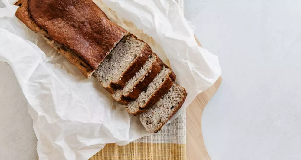 Bananenbrood in plakken op houten plank.