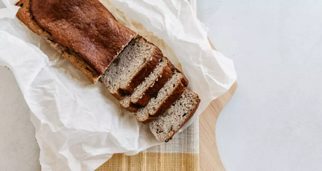 Bananenbrood in plakken op houten plank.