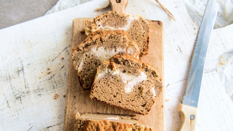 Plakken bananenbrood met roomvulling op houten plank.
