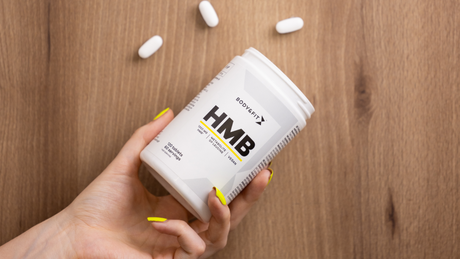 Body&Fit HMB supplement in hand met gele nagels.
