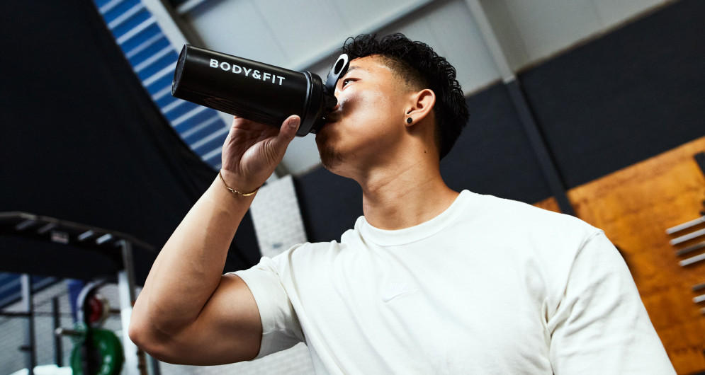 Man drinkt uit Body&Fit shaker in sportschool.
