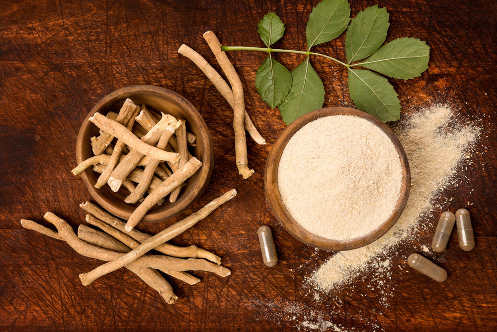 Ashwagandha en racines, poudre et gélules sur fond en bois.