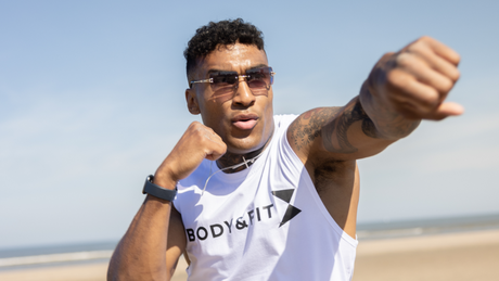 Man in sportkleding traint bokstechniek op het strand.