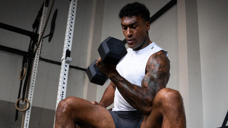 Man doing seated dumbbell curl in gym.