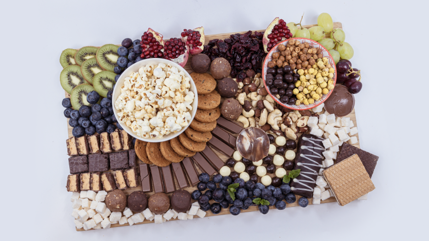 Bunter Snackteller mit Popcorn, Keksen, Schokolade, Trockenfrüchten und frischem Obst.