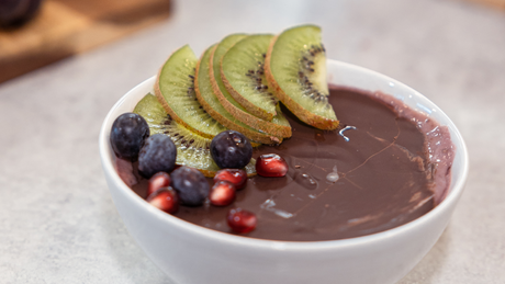 Açaï bowl au chocolat garni de kiwi, grenade et myrtilles.
