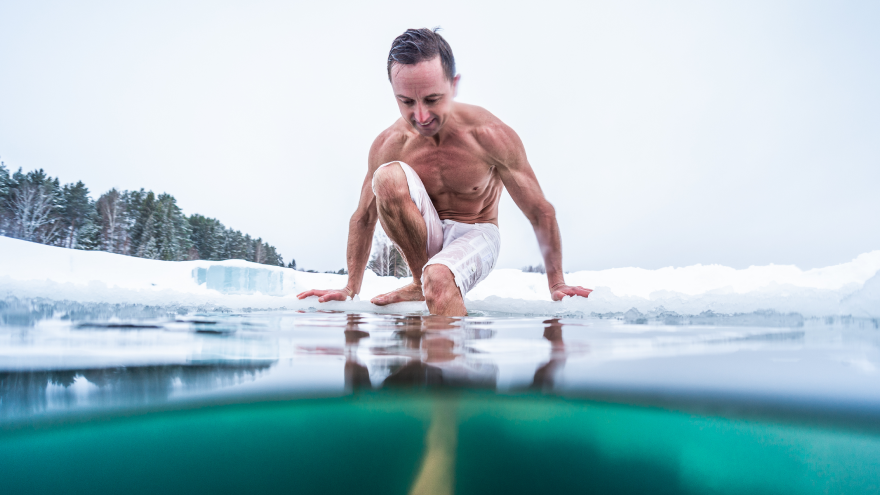 Homme torse nu entrant dans un lac glacé.