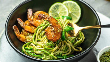 Zucchini noodles with grilled shrimp and lime slices.