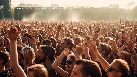 Menschenmenge jubelt bei Musikfestival in der Abendsonne.