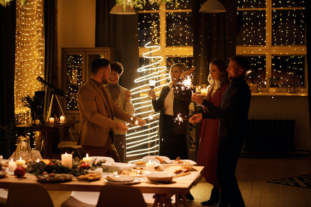 Feierliche Dinnerparty mit Freunden in weihnachtlich beleuchtetem Raum.