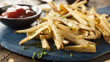 Crispy baked fries served with ketchup on a dark plate.
