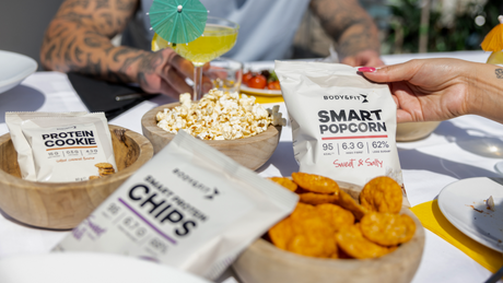 Body&Fit Smart Popcorn and protein snacks on outdoor table.