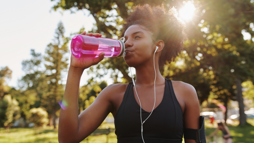 Femme buvant de l’eau après le sport dans un parc.