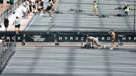 Athleten bei einem HYROX-Wettkampf, die funktionelle Übungen in einer Indoor-Arena absolvieren