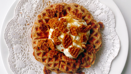 Waffel mit Spekulatius-Stückchen und Sahne auf weißem Spitzendeckchen.