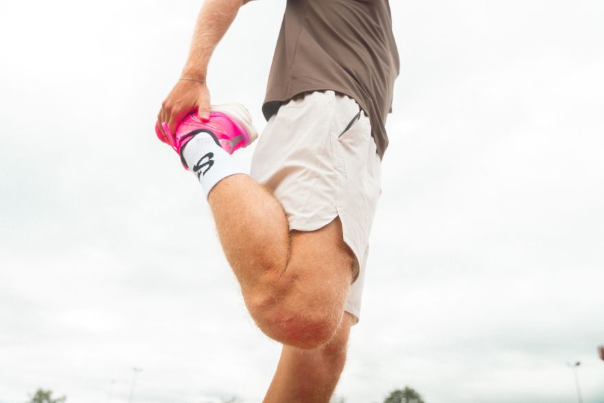 Runner doing a standing quad stretch, holding one foot behind him, as part of his half marathon preparation