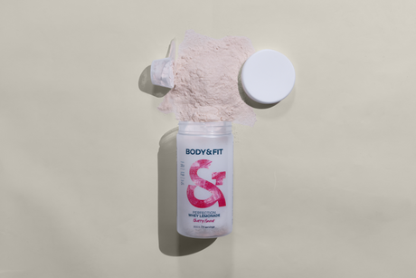Body&Fit Perfection Whey Lemonade Dose in der Geschmacksrichtung Cherry, geöffnet mit herausfallendem Eiweißpulver vor neutralem Hintergrund.