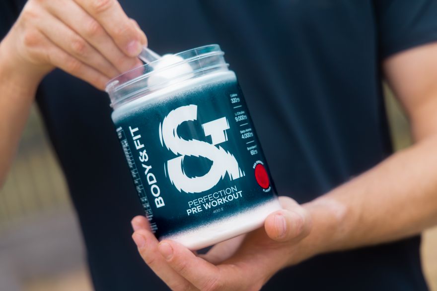Homme prélevant une dose de Body & Fit Perfection Pre Workout dans le pot