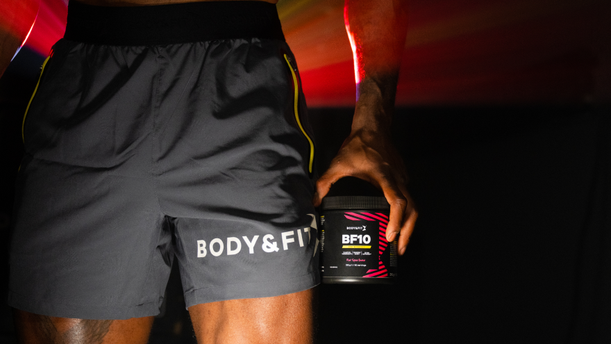 Mann hält Body&Fit-Pre-Workout in Hand mit dynamischem Lichteffekt.