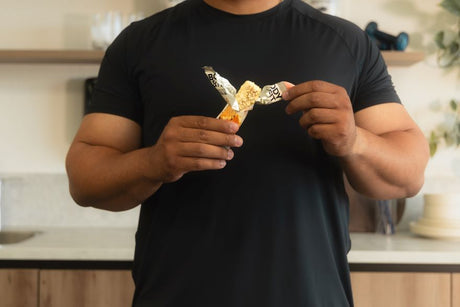 Homme cassant une barre protéinée Body & Fit pour montrer sa texture