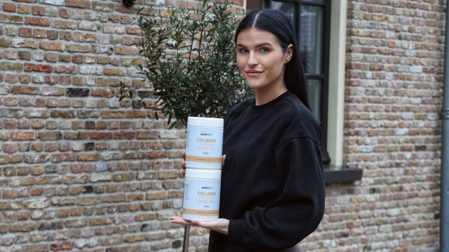 Vrouw houdt twee potten collageen supplement vast.