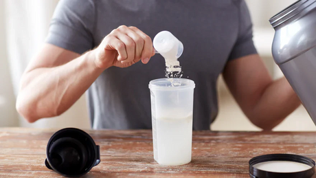 Homme versant de la protéine en poudre dans un shaker.