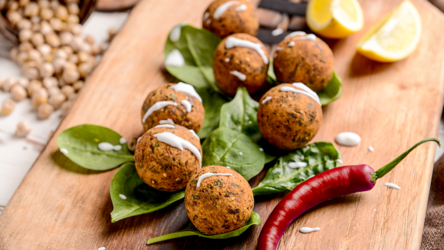 Falafel bites on spinach leaves with chili pepper and lemon slices.