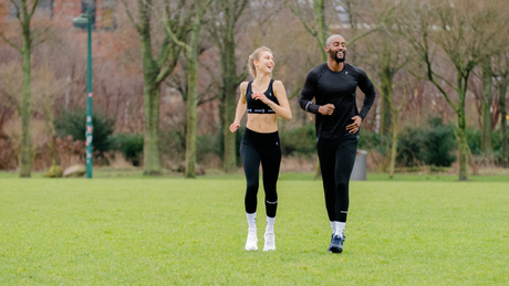 Man and woman jogging together in green park.