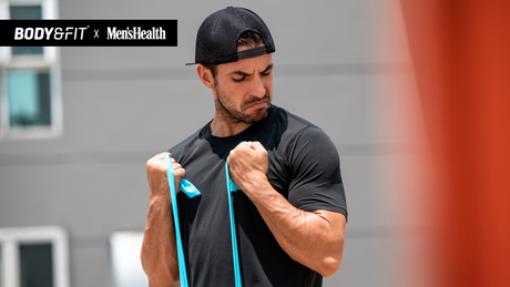 Man doing resistance band curls in Body&Fit x Men’s Health campaign.