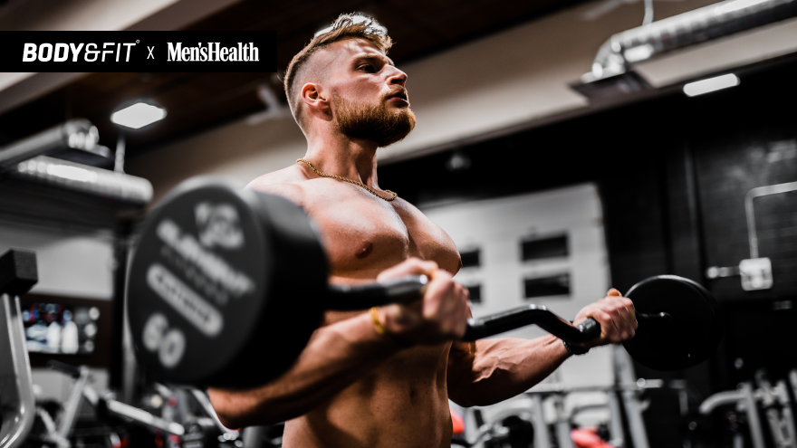 Homme torse nu soulevant une barre en salle de sport.