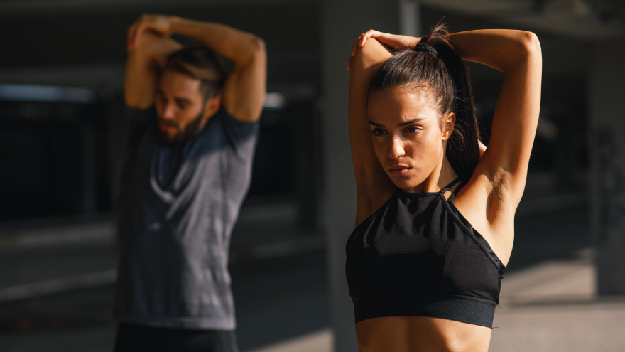 Donna e uomo si riscaldano con stretching braccia.