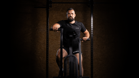 Man on air bike in gym wearing Body&Fit apparel.