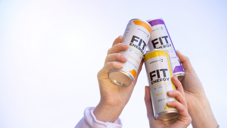 Drie handen houden blikjes Body&Fit Fit Energy omhoog.