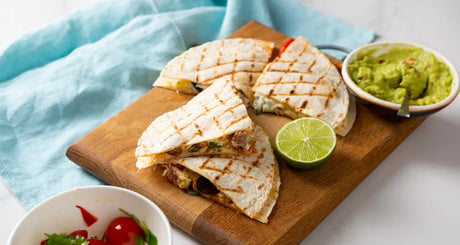 Grilled quesadillas served with lime, guacamole, and fresh salsa.