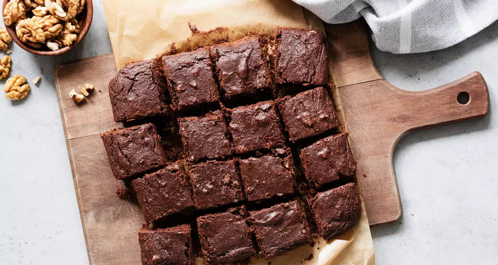 Sliced chocolate brownies on wooden board with walnuts.