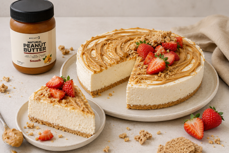 High protein cheesecake zonder oven met pindakaas swirl, verse aardbeien en krokante bodem, geserveerd naast een pot Body&Fit Natural Peanut Butter.